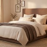 Chambre lumineuse avec une tête de lit en tissu bouclé marron, lit beige, jeté en tricot et décoration murale naturelle.