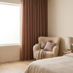 Chambre moderne avec rideaux marron texturés, un fauteuil confortable et un lit aux tons neutres.