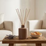 Diffuseur à bâtonnets en céramique brune sur une table en bois avec de la lavande et des écorces d'agrumes.