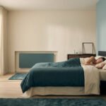 Une femme dort paisiblement dans un lit avec un radiateur design assorti aux couleurs de la chambre sur le mur.
