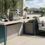Une terrasse moderne avec une machine à café sur une console entourée de plantes et d'un canapé confortable.
