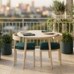 Balcon aménagé avec une table ronde, deux chaises à coussins vert foncé et plusieurs plantes en pots.