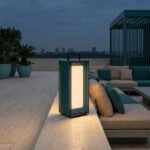 Une lanterne moderne bleu pétrole éclaire une terrasse chic au crépuscule avec un salon extérieur et une vue urbaine.