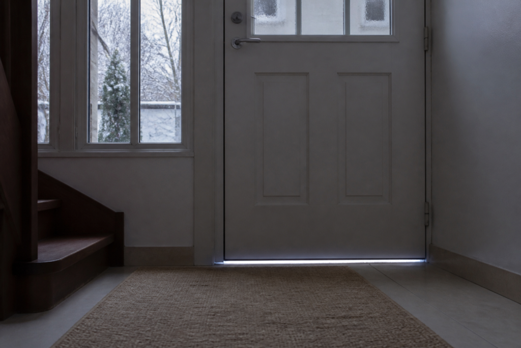 Filet de lumière visible sous une porte d’entrée laissant passer un courant d’air