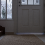 Filet de lumière visible sous une porte d’entrée laissant passer un courant d’air