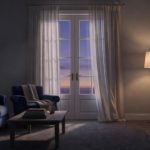 Porte-fenêtre d'un salon au crépuscule, rideau légèrement agité par un courant d'air